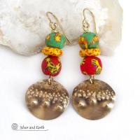 Bold and unique - these gold brass dangle earrings will surely brighten your day! They feature bright and colorful African glass beads with beautiful hues of green, red and yellow. They are accented with handcrafted gold brass dangles with a hammered organic texture. The African beads are handcrafted by artisans in Ghana from recycled glass by a traditional process passed down thru many generations. These earrings have a bohemian Afrocentric style with lots of fashionable flair! 