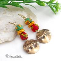 Bold and unique - these gold brass dangle earrings will surely brighten your day! They feature bright and colorful African glass beads with beautiful hues of green, red and yellow. They are accented with handcrafted gold brass dangles with a hammered organic texture. The African beads are handcrafted by artisans in Ghana from recycled glass by a traditional process passed down thru many generations. These earrings have a bohemian Afrocentric style with lots of fashionable flair! 
