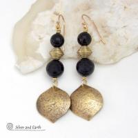 These handcrafted earrings feature gold brass dangles with a hammered raw silk texture accented with black onyx gemstones and brass beads. They have a modern boho chic style with a touch of Egyptian inspired flair that coordinates beautifully with all wardrobe types. Perfect for women that love artisan handcrafted jewelry that makes a bold statement. Handmade in the USA by Silver and Earth Jewelry. 