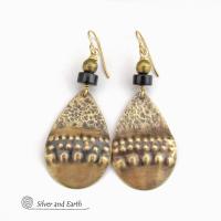 These handcrafted earrings feature textured gold brass teardrop dangles accented with matte black jasper stones and brass beads. They have an exotic, boho tribal vibe that makes a bold statement. 