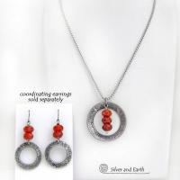 This handcrafted pendant necklace features a silver tone pewter circle with a hand stamped texture accented with a stack of faceted orange fire agate gemstones that dangle in front. It has a classic, earthy modern style that coordinates well with all wardrobe types. Matching earrings sold separately.