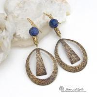 These long gold brass hoop earrings have a hand stamped texture and are accented with faceted blue lapis lazuli gemstones and brass beads. They have an exotic chic design that has an Egyptian inspired vibe and flair. Suitable for any occasion - they'll look great dressed up or down. Perfect for women that love to wear artisan handcrafted jewelry that makes a bold statement. Handmade in the USA by Silver and Earth Jewelry. 