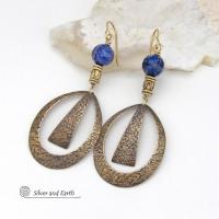 These long gold brass hoop earrings have a hand stamped texture and are accented with faceted blue lapis lazuli gemstones and brass beads. They have an exotic chic design that has an Egyptian inspired vibe and flair. Suitable for any occasion - they'll look great dressed up or down. Perfect for women that love to wear artisan handcrafted jewelry that makes a bold statement. Handmade in the USA by Silver and Earth Jewelry. 