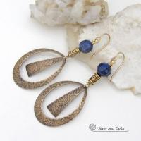 These long gold brass hoop earrings have a hand stamped texture and are accented with faceted blue lapis lazuli gemstones and brass beads. They have an exotic chic design that has an Egyptian inspired vibe and flair. Suitable for any occasion - they'll look great dressed up or down. Perfect for women that love to wear artisan handcrafted jewelry that makes a bold statement. Handmade in the USA by Silver and Earth Jewelry. 