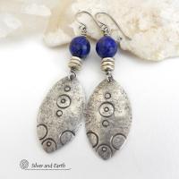 These handcrafted sterling silver earrings have an exotic, Egyptian inspired vibe. The design consists of sterling dangles with a hand stamped texture accented with faceted lapis lazuli gemstones and small pewter beads. Bold and unique - they'll make a striking statement and will add a touch of cultural exotic charm to any outfit.