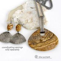 This handcrafted necklace features a large, chunky natural picture jasper stone accented with a handcrafted sterling silver bail. The stone has a beautiful natural pattern in various shades of brown, beige and gray. Big and bold, this necklace is a real one-of-a-kind statement piece - perfect for anyone that loves natural stones! It's reversible and can be worn on either side. Coordinating earrings sold separately. Handmade in the USA by Silver and Earth Jewelry.