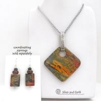 This one-of-a-kind necklace features a natural red creek jasper stone accented with a hand forged sterling silver bail. The stone has a beautiful natural pattern in earthy hues of mossy greens, brick red and orange. Coordinating earrings sold separately
