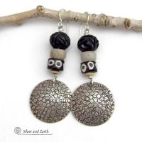 These handcrafted sterling silver earrings have an ethnic, tribal vibe. They feature African carved bone, glass and batik bone beads accented with hand stamped sterling silver dangles. Bold and striking, they'll make an exotic statement. Perfect for women that love to wear unique jewelry. Handmade in the USA by Silver and Earth Jewelry. 