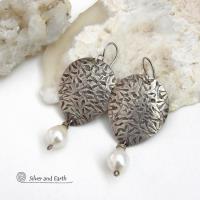 Perfect for everyday wear, these handcrafted sterling silver earrings are accented with dangling white freshwater pearls. The silver has an intricate hand stamped texture with an oxidized finish. The pearls contrast beautifully against the silver metal. They have an elegant, feminine feel with a contemporary design that looks great with all wardrobe styles. They'll make a great gift for someone born in June. Pearl is the traditional gemstone for this month. Handmade in the USA by Silver and Earth Jewelry. 