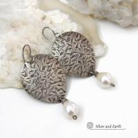 Perfect for everyday wear, these handcrafted sterling silver earrings are accented with dangling white freshwater pearls. The silver has an intricate hand stamped texture with an oxidized finish. The pearls contrast beautifully against the silver metal. They have an elegant, feminine feel with a contemporary design that looks great with all wardrobe styles. They'll make a great gift for someone born in June. Pearl is the traditional gemstone for this month. Handmade in the USA by Silver and Earth Jewelry. 