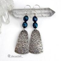 These sterling silver earrings feature handcrafted sterling silver dangles with an intricate hand stamped texture accented with deep teal blue freshwater pearls with a faceted finish.  They have a modern, elegant feel and will look great dressed up or down. They dangle from sterling silver ear wires. Handmade in the USA by Silver and Earth Jewelry. 