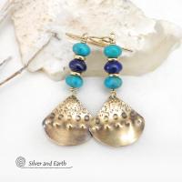 These handcrafted gold brass earrings have a unique hand textured design and are accented with a stack of blue lapis lazuli and turquoise gemstones separated with small brass beads. These handcrafted earrings showcase a unique blend of textures, colors and patterns, perfect for adding a touch of bohemian style to any outfit. 