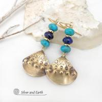 These handcrafted gold brass earrings have a unique hand textured design and are accented with a stack of blue lapis lazuli and turquoise gemstones separated with small brass beads. These handcrafted earrings showcase a unique blend of textures, colors and patterns, perfect for adding a touch of bohemian style to any outfit. Silver and Earth is a small business that makes handmade jewelry and who is known for her unique exclusive designs. 