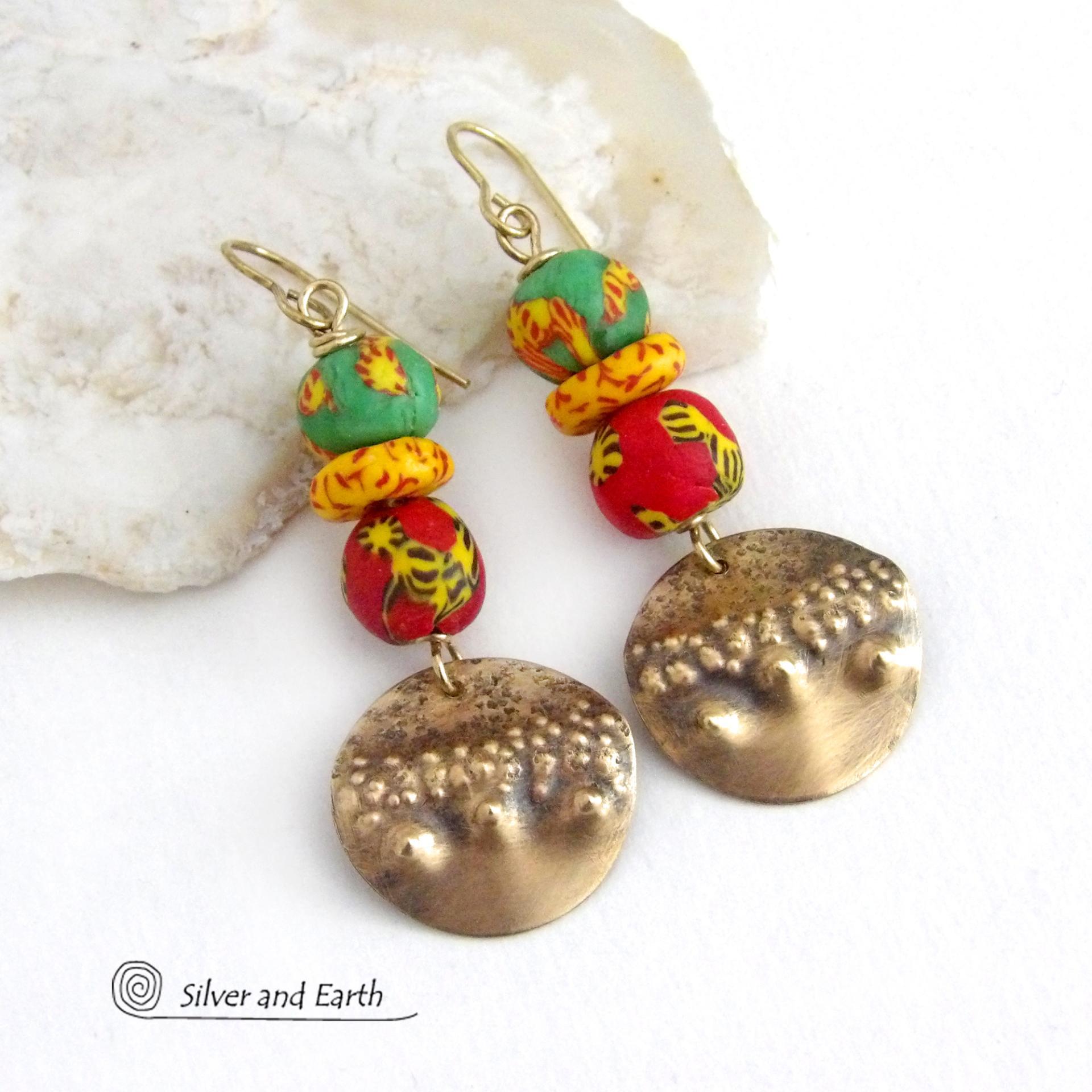 Bold and unique - these gold brass dangle earrings will surely brighten your day! They feature bright and colorful African glass beads with beautiful hues of green, red and yellow. They are accented with handcrafted gold brass dangles with a hammered organic texture. The African beads are handcrafted by artisans in Ghana from recycled glass by a traditional process passed down thru many generations. These earrings have a bohemian Afrocentric style with lots of fashionable flair! 