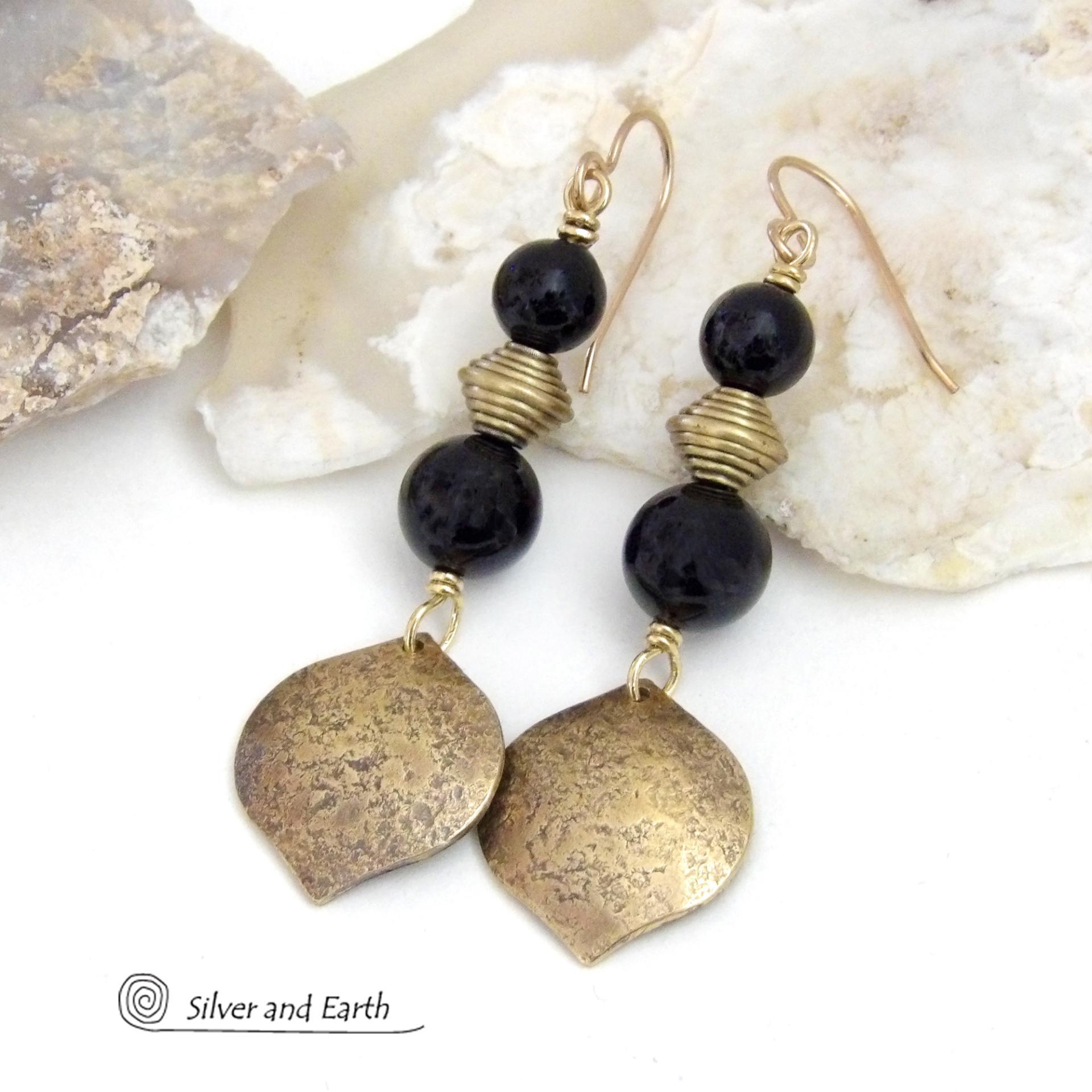 These handcrafted earrings feature gold brass dangles with a hammered raw silk texture accented with black onyx gemstones and brass beads. They have a modern boho chic style with a touch of Egyptian inspired flair that coordinates beautifully with all wardrobe types. Perfect for women that love artisan handcrafted jewelry that makes a bold statement. Handmade in the USA by Silver and Earth Jewelry. 