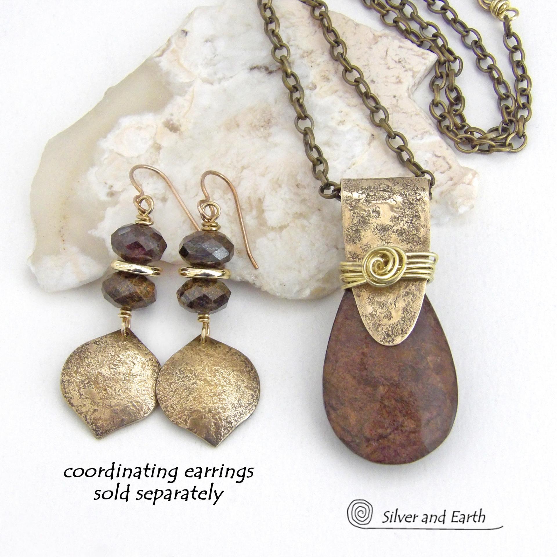 This handcrafted necklace features a natural bronzite gemstone accented with a gold brass bail. The stone has a beautiful chocolate brown hue with a subtle golden shimmer. Bronzite is a mineral that shares characteristics with rock that is found in meteorites, such as iron. It's this blend of several minerals which gives bronzite its unique mottled characteristic. The necklace has an earthy, modern style that coordinates beautifully with all wardrobe types. 