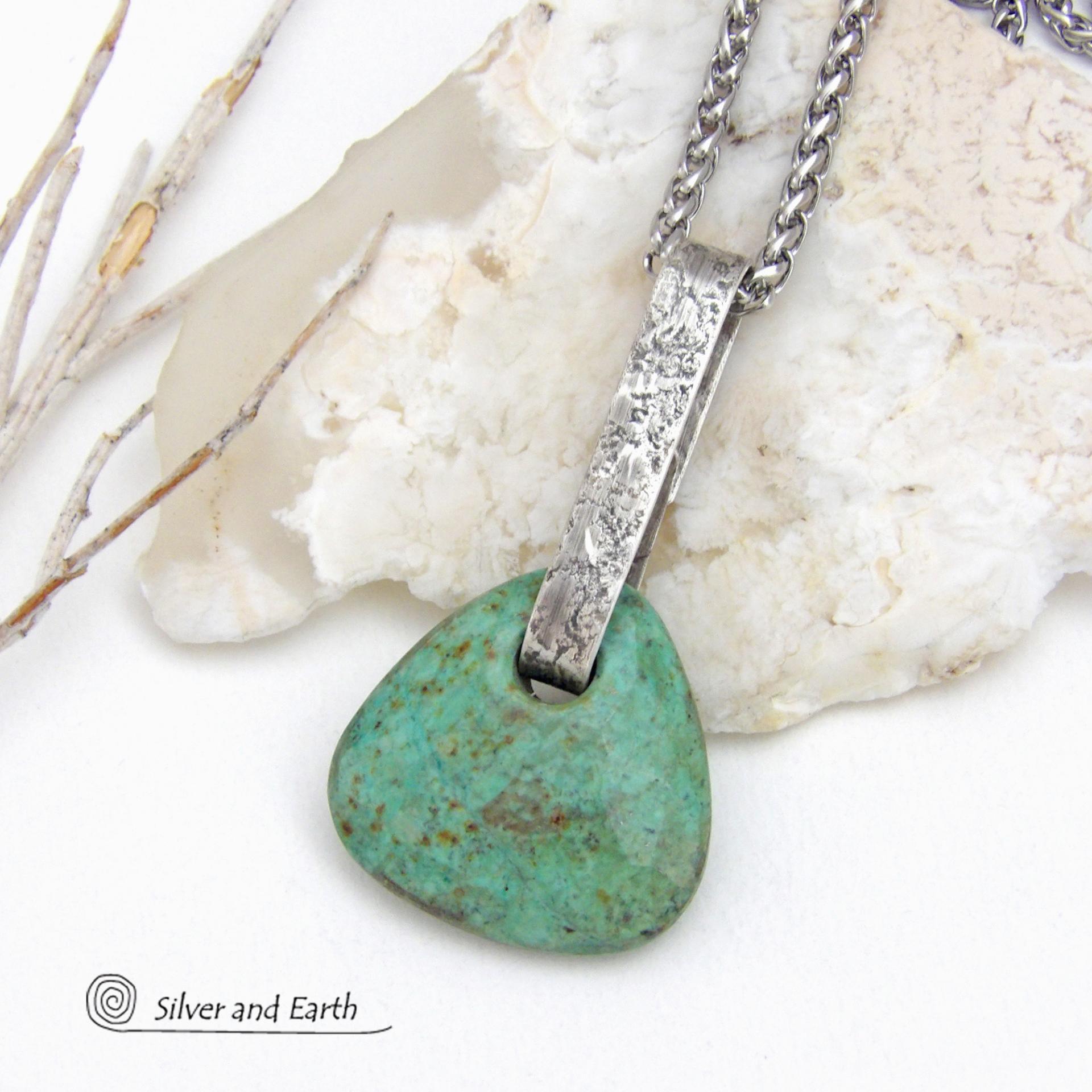 This one-of-a-kind pendant necklace features a beautiful chunky natural chrysocolla gemstone with a faceted finish. The stone is a beautiful shade of bluish-green which resembles turquoise. It hangs from a hand forged solid sterling silver bail with a lightly hammered organic texture. It's reversible. Unique and one-of-a-kind, it's sure to make a statement. Handmade in the USA by Silver and Earth Jewelry.