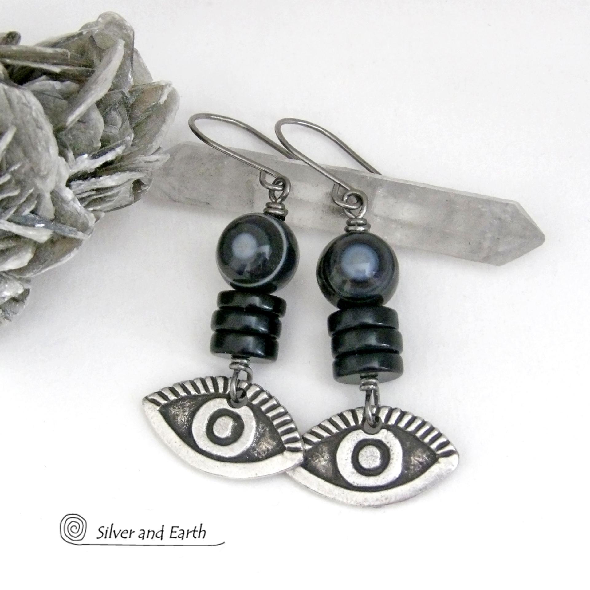 These unique earrings feature black eye agate and onyx stones accented with silver pewter "evil eye" charms. When cut at the right angle, this type of agate reveals a series of concentric rings that resembles the human eye. Evil eye symbolism has been around for centuries. The belief is that when worn -- evil eye jewelry will provide a level of protection against the envy and negative energy of others and perhaps bring the wearer good luck.