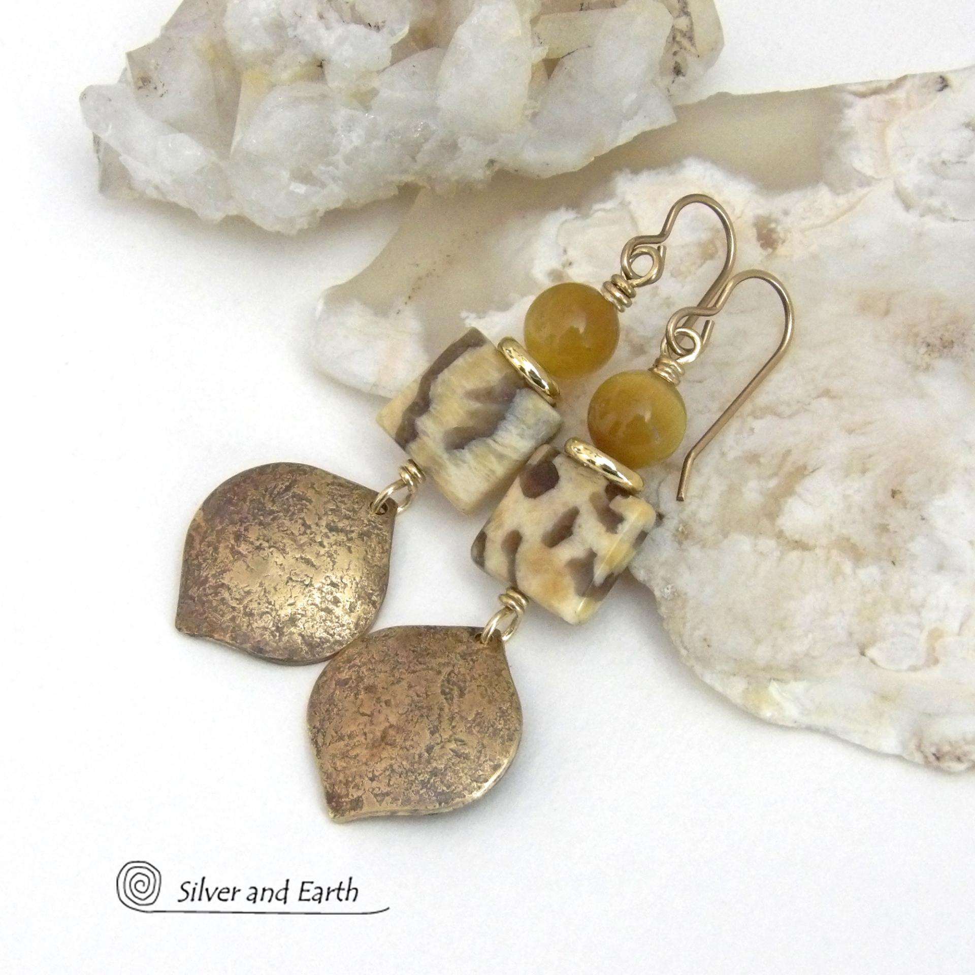 These handcrafted earrings feature shiny gold brass dangles with a hammered raw silk texture accented with graphic feldspar and golden tiger's eye gemstones and shiny brass beads. Graphic feldspar is a type of moonstone that has smoky quartz inclusions which creates unique natural patterns. They have an elegant, modern chic style that looks great dressed up or down. Handmade in the USA by Silver and Earth Jewelry. Total length of approx. 2-3/8" from top of brass ear wires and 3/4" at widest point.