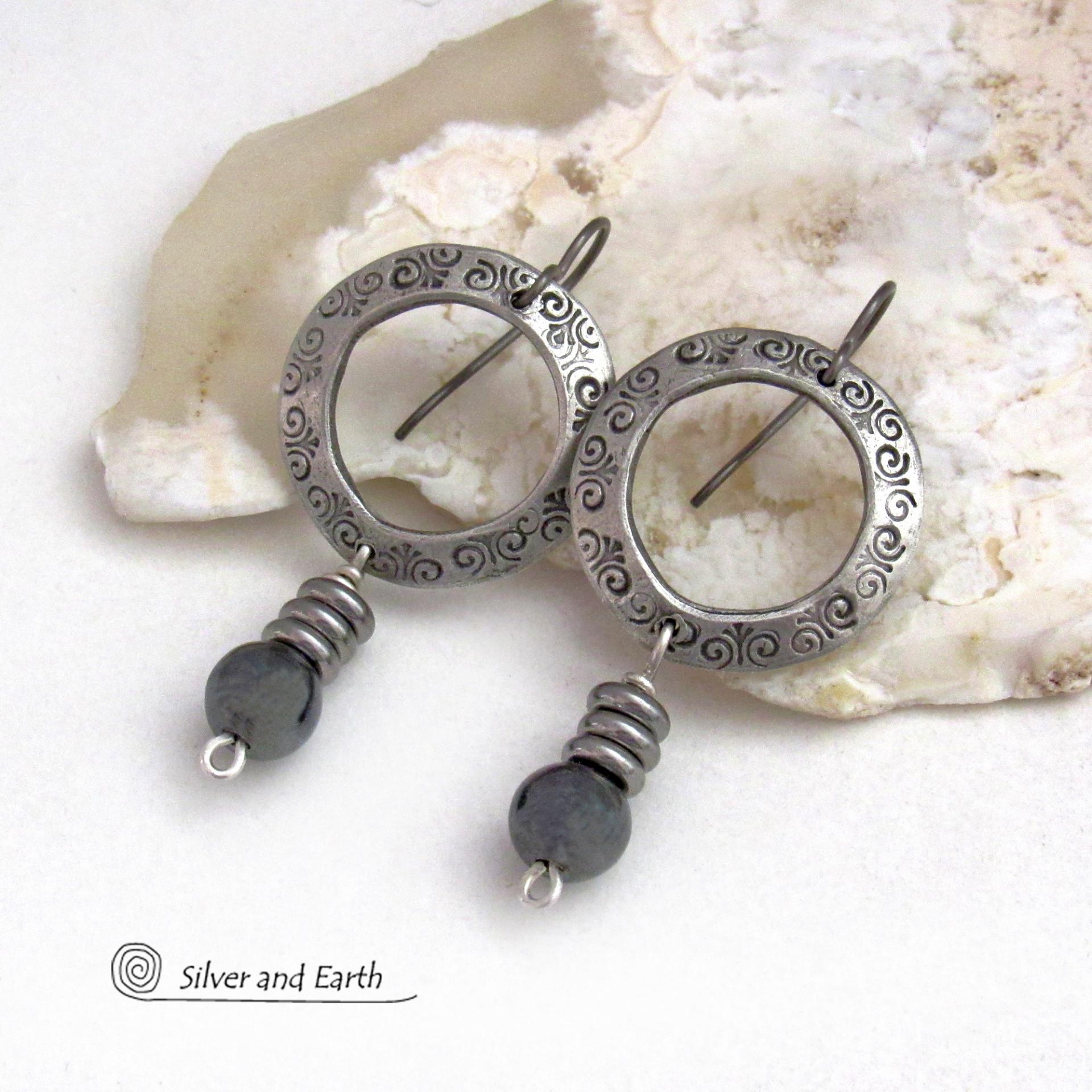 These silver pewter hoop earrings have a hand stamped texture and are accented with hematite gemstones and stainless steel beads. The stones have a metallic gray hue which cast offs a bit of natural shimmer & shine. They have a modern chic style that coordinates beautifully with all wardrobe styles. Earrings are lightweight and comfortable to wear. Handmade in the USA by Silver and Earth Jewelry. 