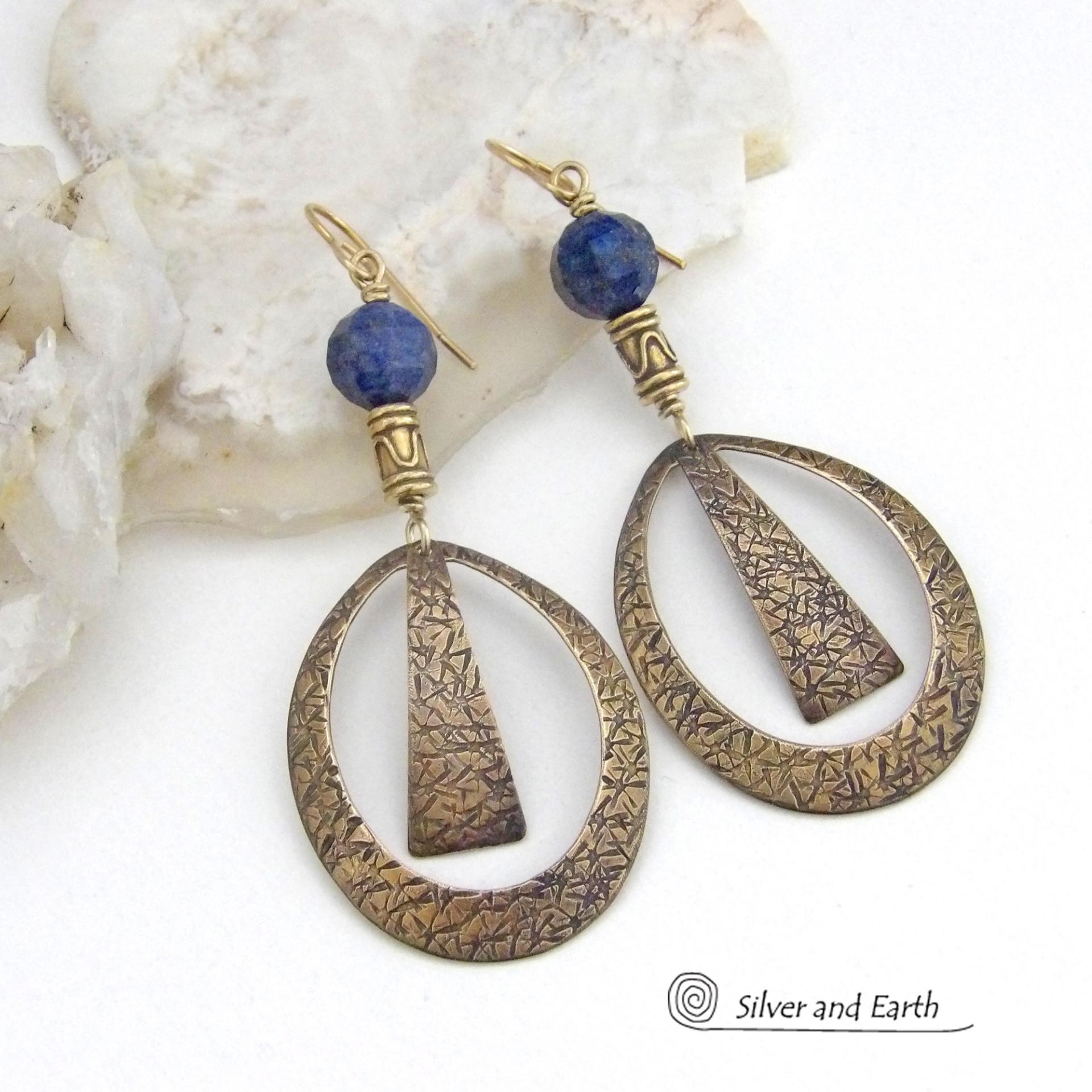 These long gold brass hoop earrings have a hand stamped texture and are accented with faceted blue lapis lazuli gemstones and brass beads. They have an exotic chic design that has an Egyptian inspired vibe and flair. Suitable for any occasion - they'll look great dressed up or down. Perfect for women that love to wear artisan handcrafted jewelry that makes a bold statement. Handmade in the USA by Silver and Earth Jewelry. 