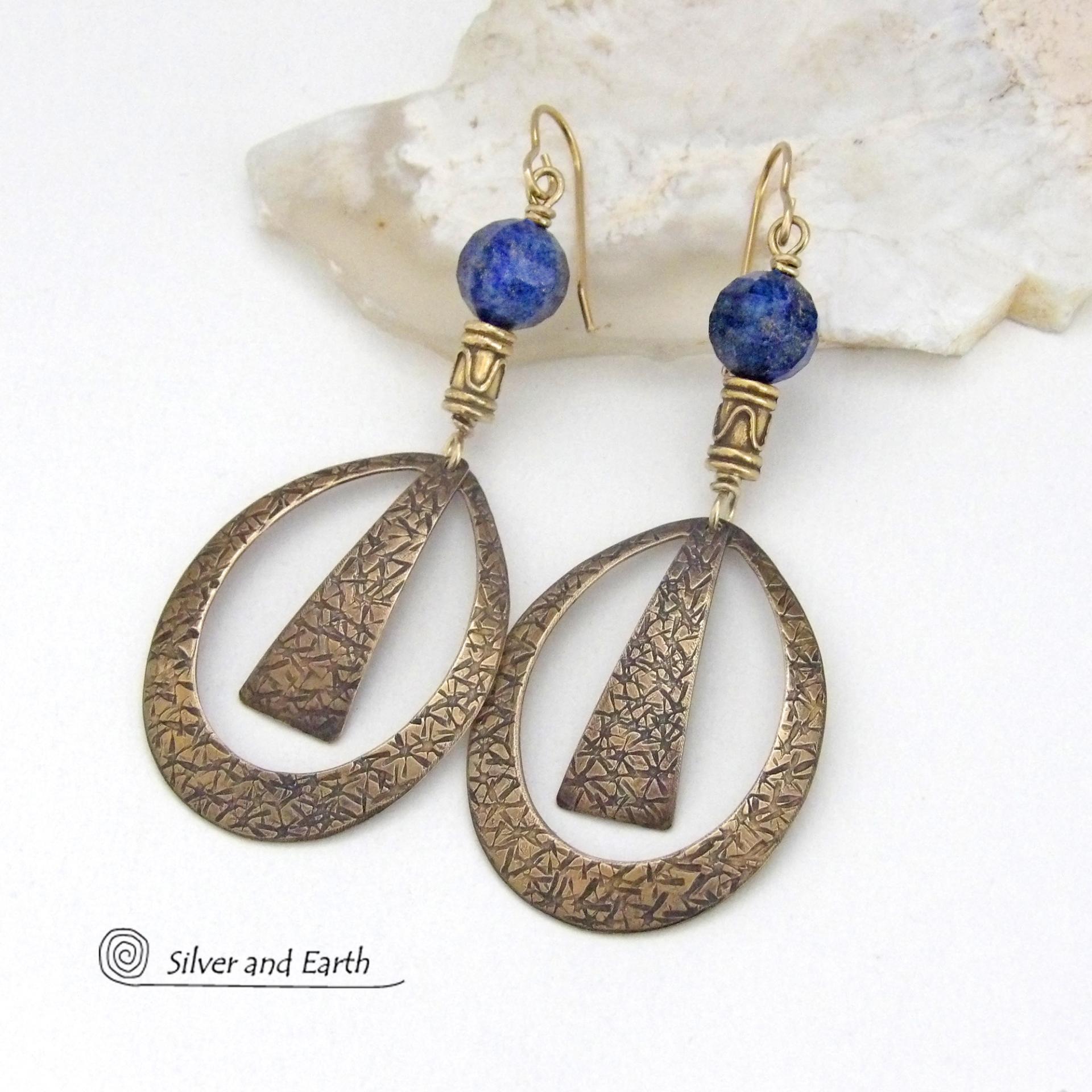 These long gold brass hoop earrings have a hand stamped texture and are accented with faceted blue lapis lazuli gemstones and brass beads. They have an exotic chic design that has an Egyptian inspired vibe and flair. Suitable for any occasion - they'll look great dressed up or down. Perfect for women that love to wear artisan handcrafted jewelry that makes a bold statement. Handmade in the USA by Silver and Earth Jewelry. 