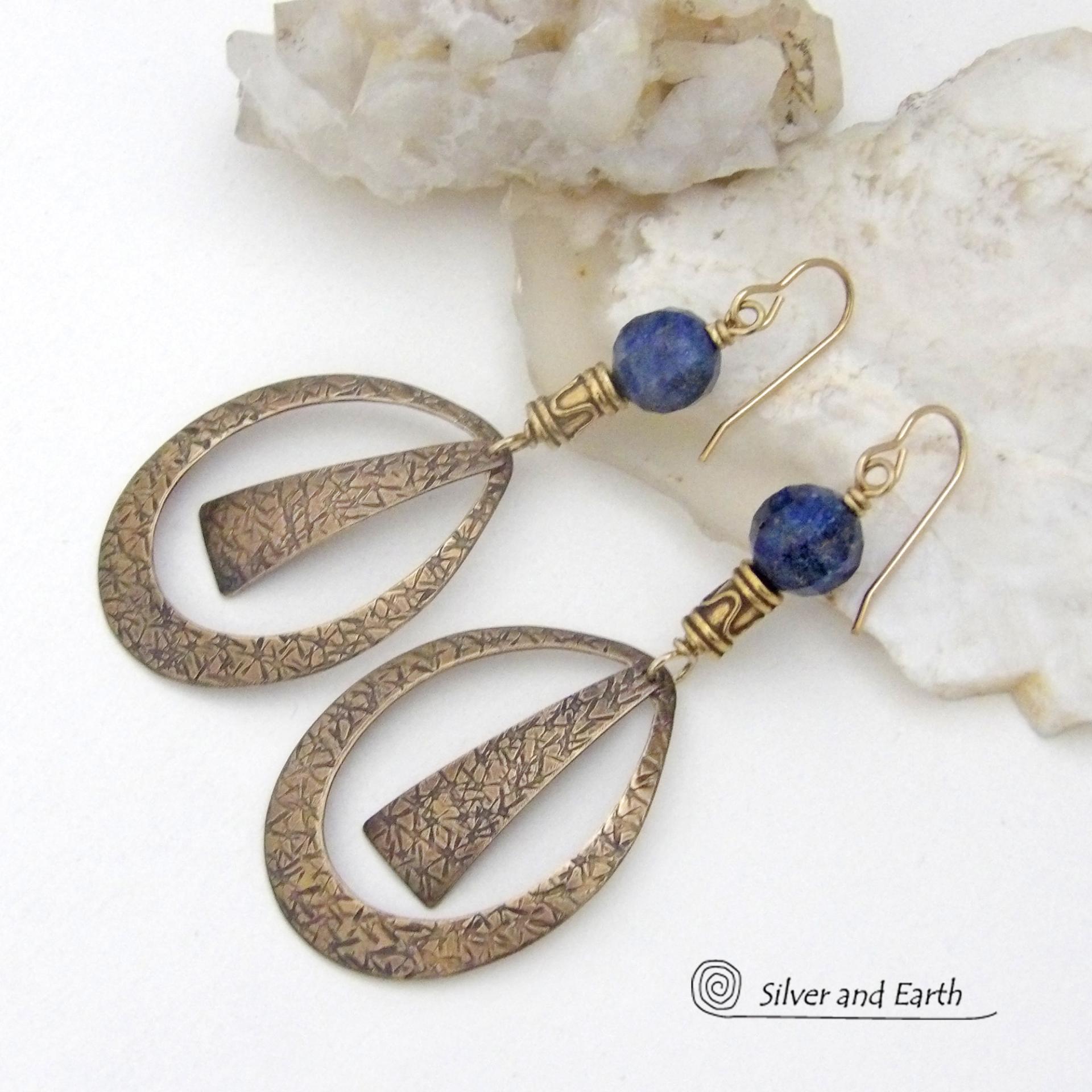 These long gold brass hoop earrings have a hand stamped texture and are accented with faceted blue lapis lazuli gemstones and brass beads. They have an exotic chic design that has an Egyptian inspired vibe and flair. Suitable for any occasion - they'll look great dressed up or down. Perfect for women that love to wear artisan handcrafted jewelry that makes a bold statement. Handmade in the USA by Silver and Earth Jewelry. 