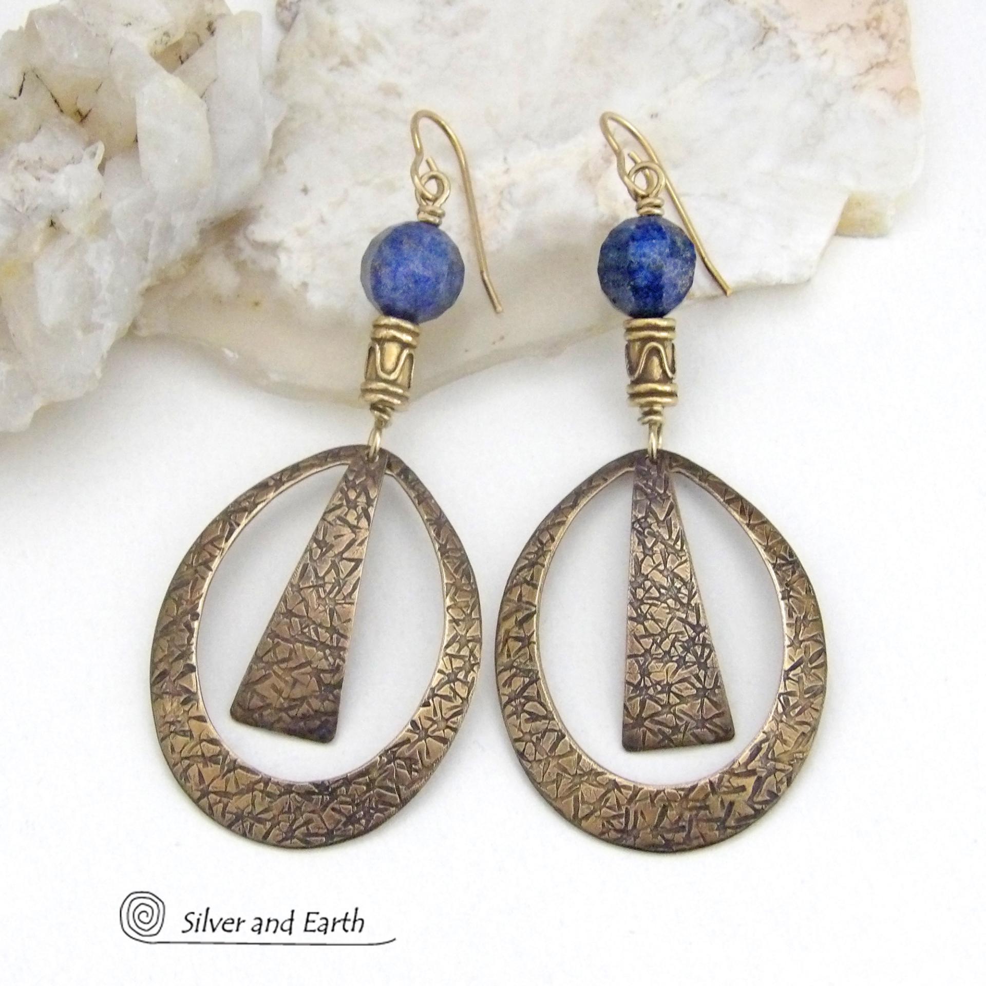 These long gold brass hoop earrings have a hand stamped texture and are accented with faceted blue lapis lazuli gemstones and brass beads. They have an exotic chic design that has an Egyptian inspired vibe and flair. Suitable for any occasion - they'll look great dressed up or down. Perfect for women that love to wear artisan handcrafted jewelry that makes a bold statement. Handmade in the USA by Silver and Earth Jewelry. 