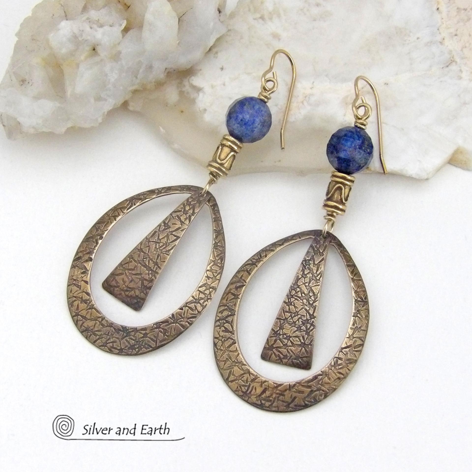 These long gold brass hoop earrings have a hand stamped texture and are accented with faceted blue lapis lazuli gemstones and brass beads. They have an exotic chic design that has an Egyptian inspired vibe and flair. Suitable for any occasion - they'll look great dressed up or down. Perfect for women that love to wear artisan handcrafted jewelry that makes a bold statement. Handmade in the USA by Silver and Earth Jewelry. 