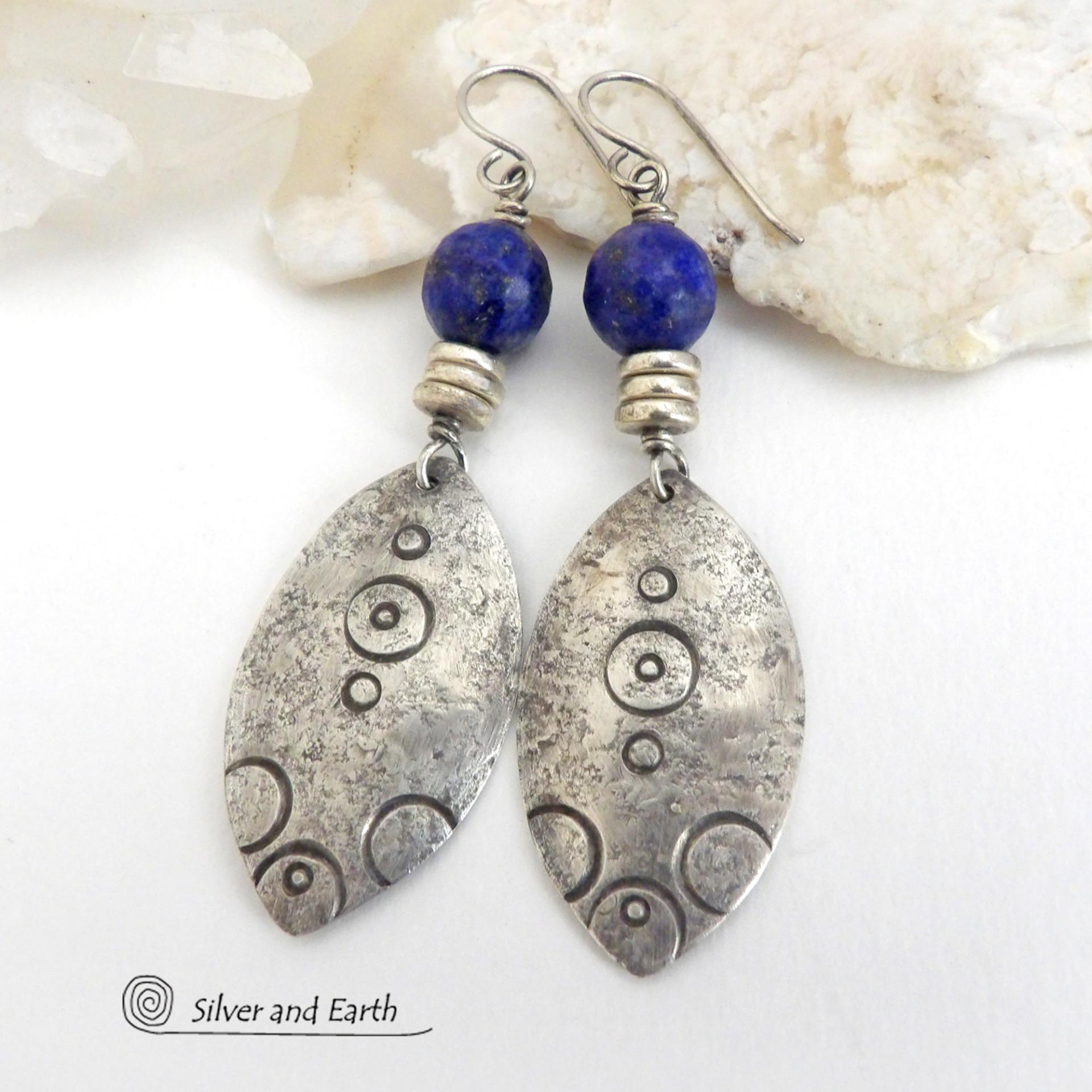 These handcrafted sterling silver earrings have an exotic, Egyptian inspired vibe. The design consists of sterling dangles with a hand stamped texture accented with faceted lapis lazuli gemstones and small pewter beads. Bold and unique - they'll make a striking statement and will add a touch of cultural exotic charm to any outfit.