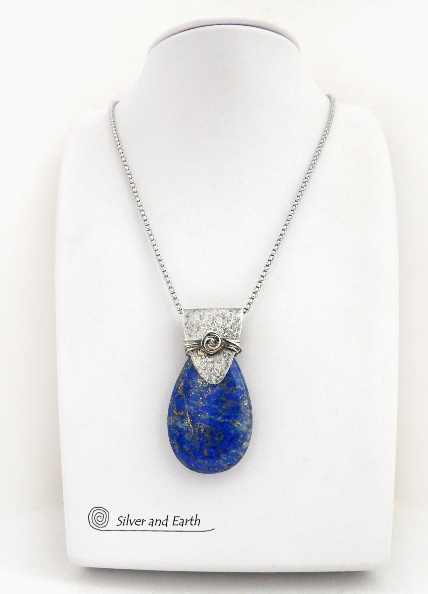 This sterling silver necklace features a natural lapis lazuli gemstone accented with a handcrafted sterling silver bail with a lightly hammered organic texture. The lapis is a beautiful shade of blue with natural sparkly pyrite inclusions.