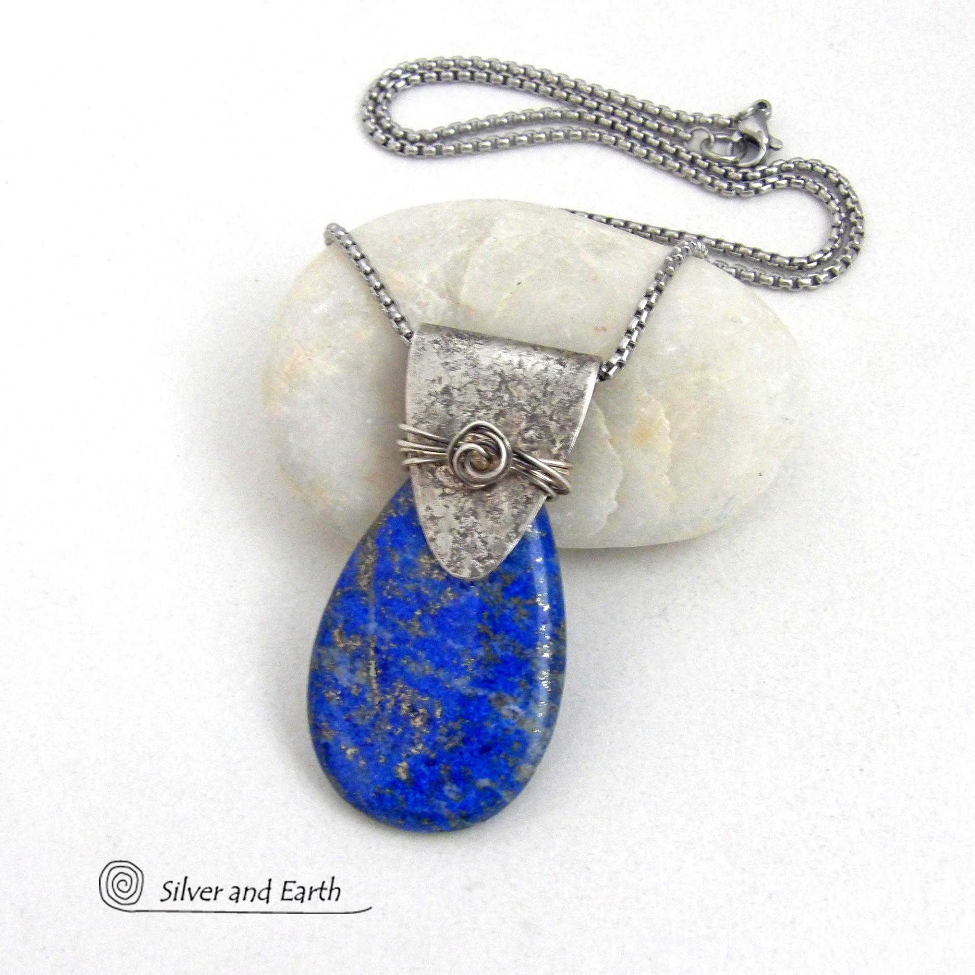 This sterling silver necklace features a natural lapis lazuli gemstone accented with a handcrafted sterling silver bail with a lightly hammered organic texture. The lapis is a beautiful shade of blue with natural sparkly pyrite inclusions.