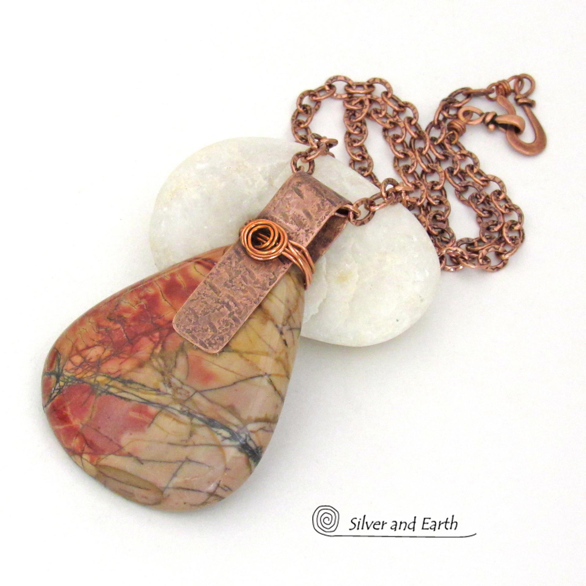 This one-of-a-kind necklace features a large stunning red creek jasper stone accented with a handcrafted copper bail. The stone has a natural pattern in beautiful earthy shades of brick red, orange and taupe with streaks of black veining. Big and bold, this necklace is a real statement piece - perfect for anyone that loves natural stones!