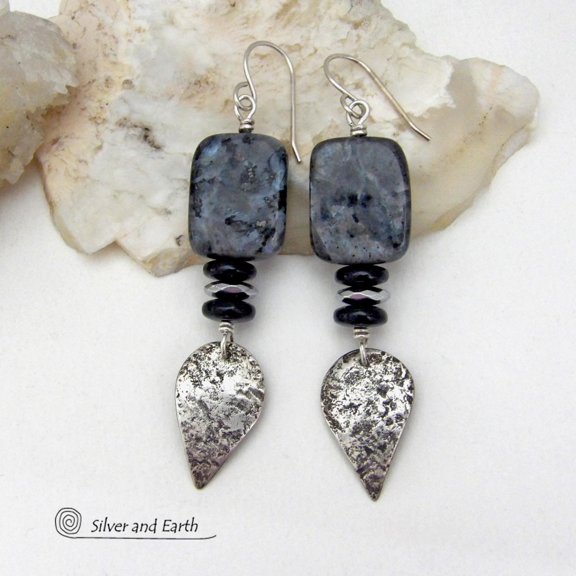 These handcrafted sterling silver earrings feature natural larvikite gemstones accented with small sterling silver dangles, black onyx and faceted silver hematite gemstones. The larvikite has a pearly, grayish black hue with iridescent flashes of light which cast off a natural shimmer & shine. They have a modern, chic contemporary style that will look great dressed up or down. Larvikite originates from the Larvik region in Norway. It's also called Norwegian moonstone and black labradorite. 