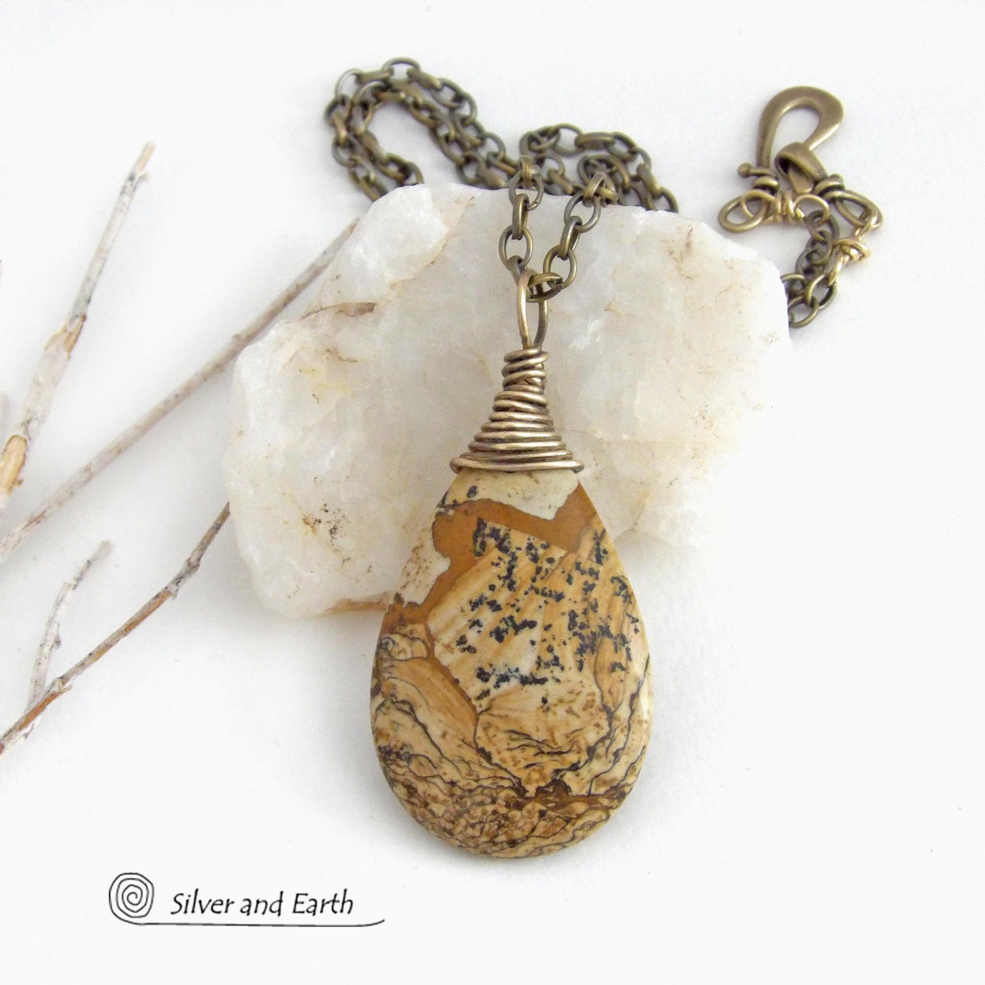 This one-of-a-kind necklace features a natural picture jasper stone wrapped in gold brass wire. The stone has an interesting matrix pattern with earthy hues of brown, tan and black. It has an earthy, simple style that coordinates beautifully with all wardrobe styles. It makes a great gift for a natural stone lover - or a nice addition to your own jewelry collection. Handmade in the USA by Silver and Earth Jewelry. Coordinating earrings sold separately.