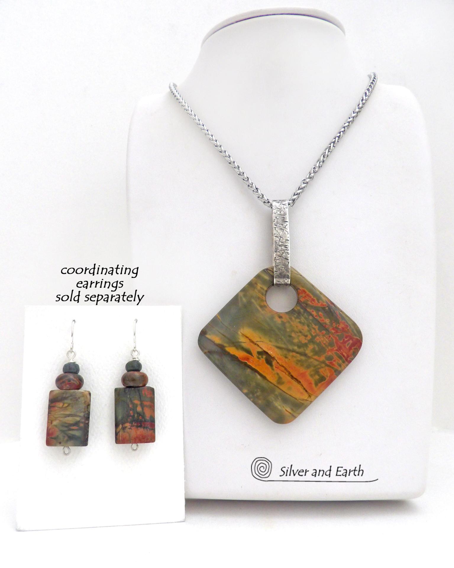 This one-of-a-kind necklace features a natural red creek jasper stone accented with a hand forged sterling silver bail. The stone has a beautiful natural pattern in earthy hues of mossy greens, brick red and orange. Coordinating earrings sold separately