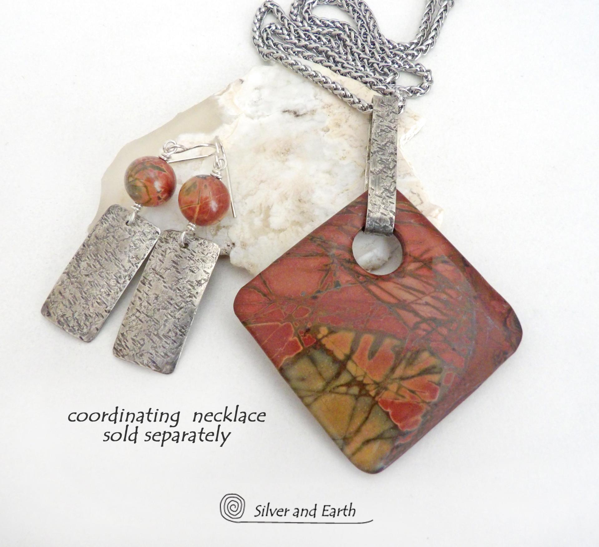 These sterling silver earrings have a modern, earthy organic flair. They feature handcrafted sterling silver rectangles with a rustic hammered texture accented with natural red creek jasper stones. The stones have a beautiful natural pattern in earthy hues of mossy greens, brick red and orange. They have a coordinating necklace which is sold separately. 