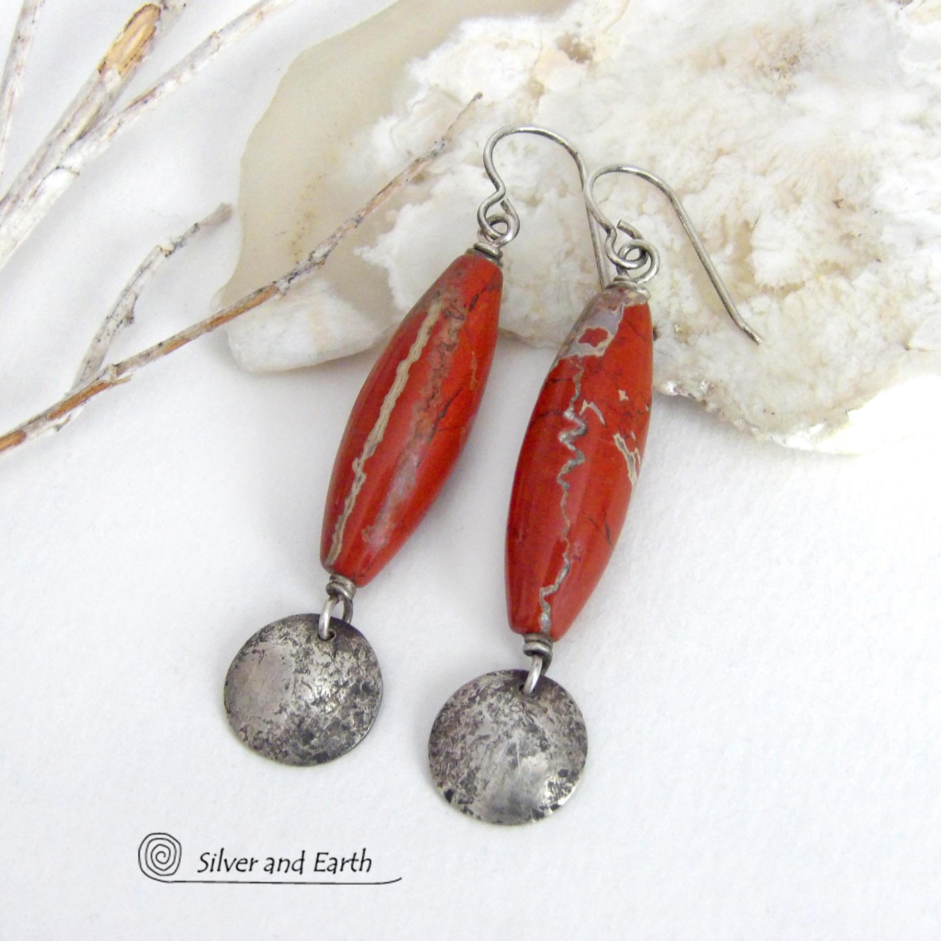 These handmade earrings feature natural red jasper gemstones accented with small hammered sterling silver dangles. The stones have a brick red hue with an interesting matrix of beige streaks and squiggly lines. They have a modern, earthy appeal that coordinates well with all wardrobe styles. They'll make a great gift for a natural stone lover - or a nice addition to your own jewelry wardrobe. They have a coordinating necklace which is sold separately. Handmade in the USA by Silver and Earth Jewelry.  
