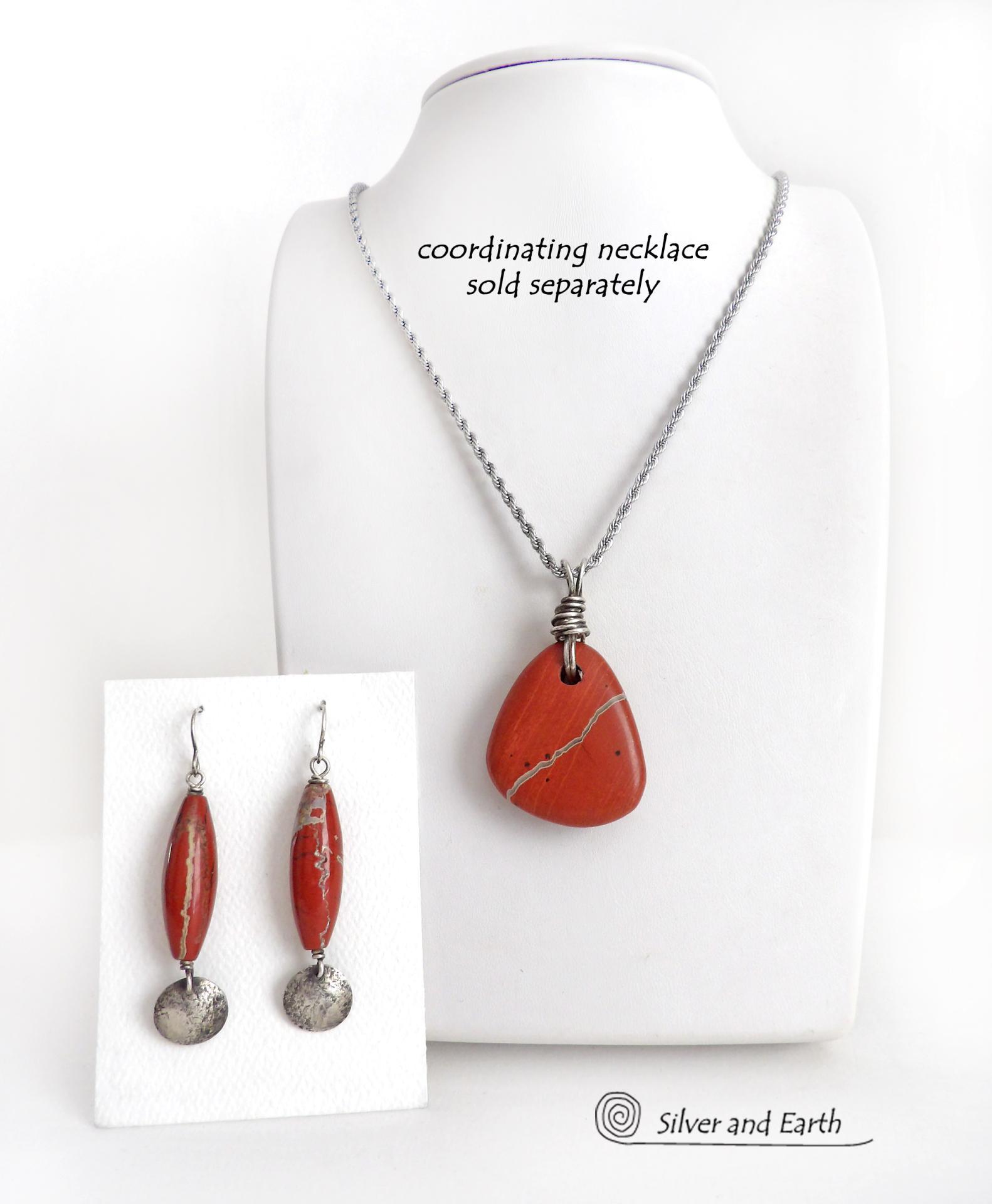 These handmade earrings feature natural red jasper gemstones accented with small hammered sterling silver dangles. The stones have a brick red hue with an interesting matrix of beige streaks and squiggly lines. They have a modern, earthy appeal that coordinates well with all wardrobe styles. They'll make a great gift for a natural stone lover - or a nice addition to your own jewelry wardrobe. They have a coordinating necklace which is sold separately. Handmade in the USA by Silver and Earth Jewelry.  