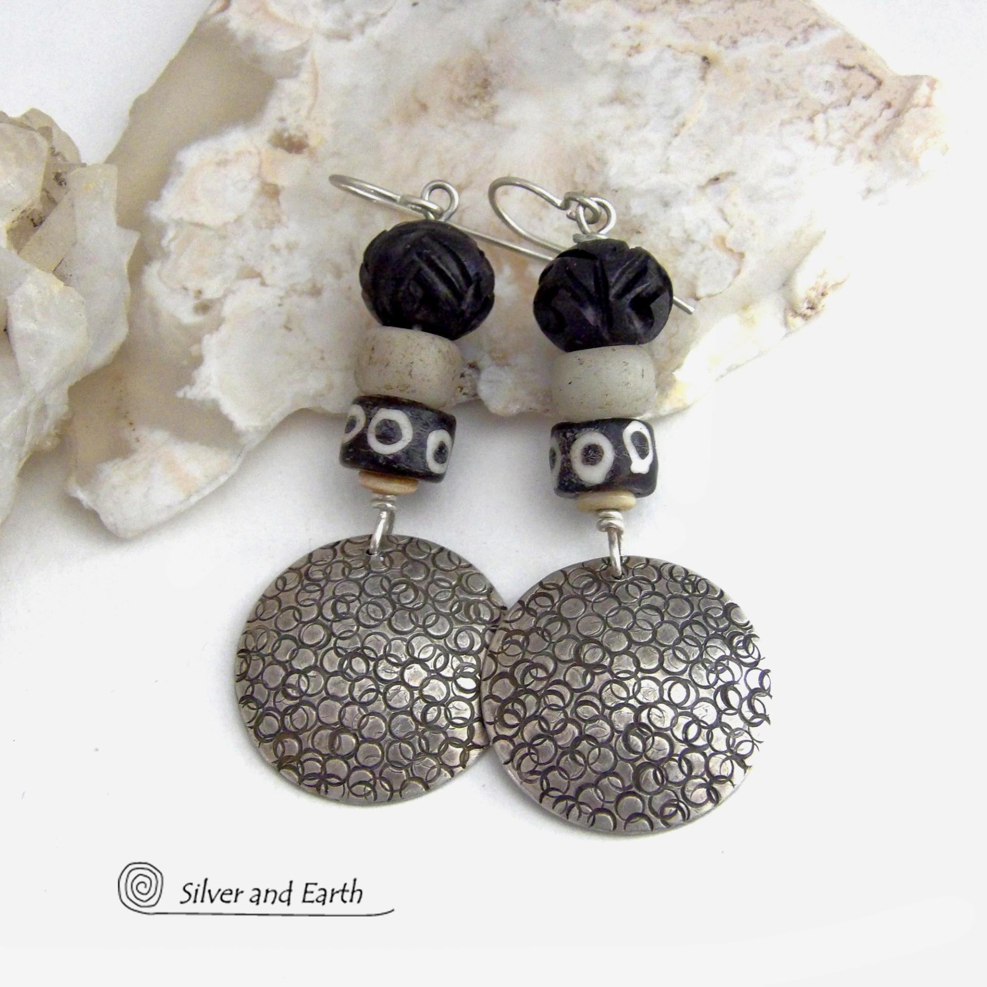 These handcrafted sterling silver earrings have an ethnic, tribal vibe. They feature African carved bone, glass and batik bone beads accented with hand stamped sterling silver dangles. Bold and striking, they'll make an exotic statement. Perfect for women that love to wear unique jewelry. Handmade in the USA by Silver and Earth Jewelry. 