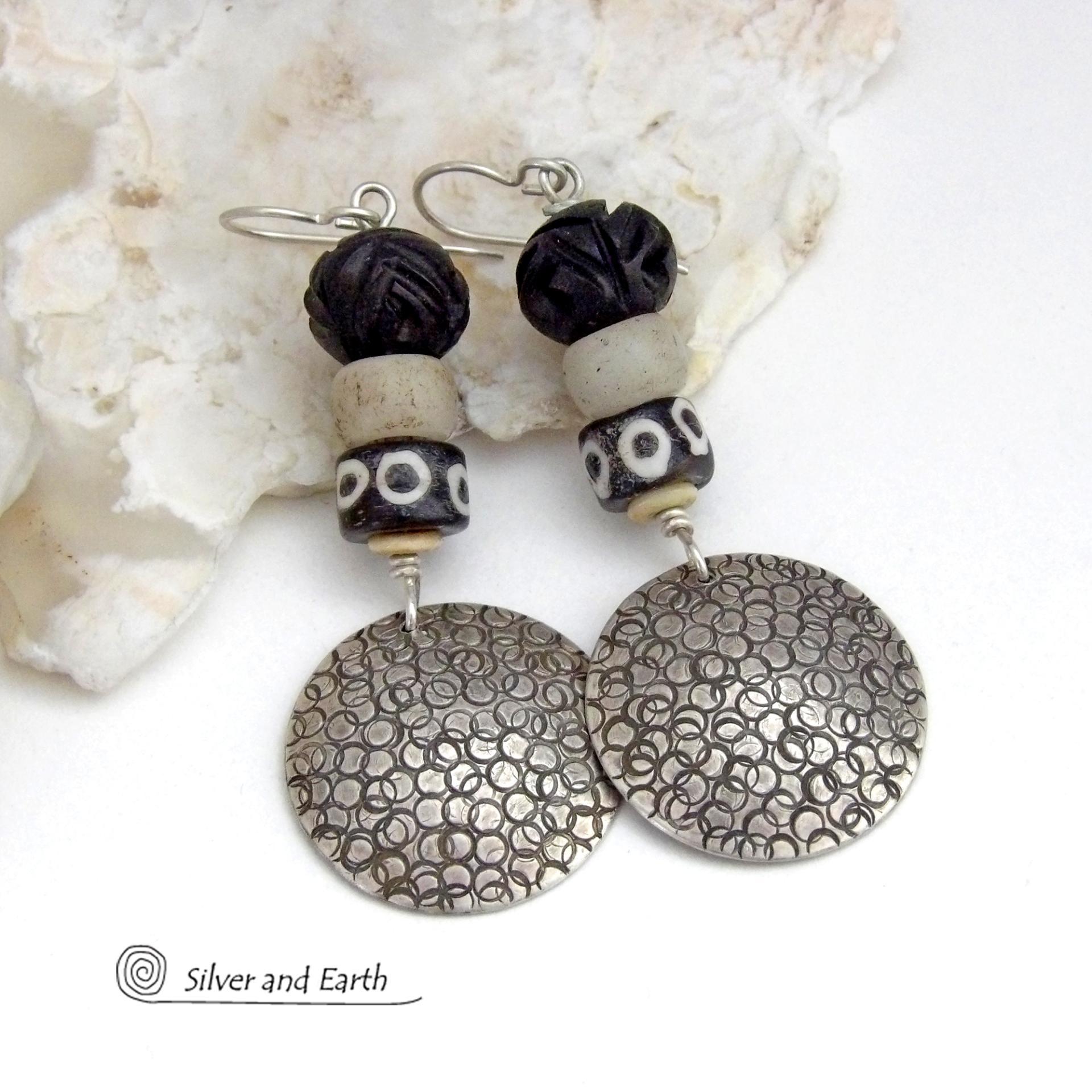 These handcrafted sterling silver earrings have an ethnic, tribal vibe. They feature African carved bone, glass and batik bone beads accented with hand stamped sterling silver dangles. Bold and striking, they'll make an exotic statement. Perfect for women that love to wear unique jewelry. Handmade in the USA by Silver and Earth Jewelry. 