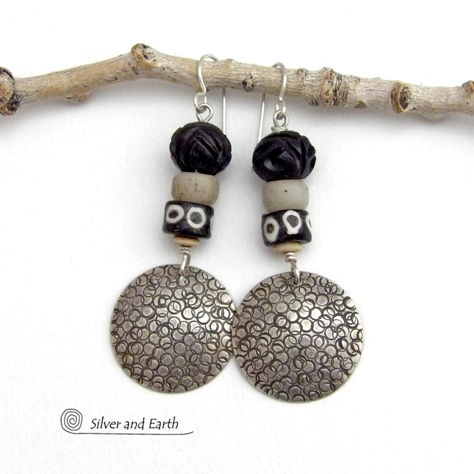 These handcrafted sterling silver earrings have an ethnic, tribal vibe. They feature African carved bone, glass and batik bone beads accented with hand stamped sterling silver dangles. Bold and striking, they'll make an exotic statement. Perfect for women that love to wear unique jewelry. Handmade in the USA by Silver and Earth Jewelry. 