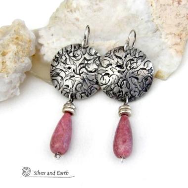 These handmade sterling silver earrings have a modern, classic design that will always be in fashion. They feature natural rhodonite gemstones dangling from textured sterling silver. The stones have a slender teardrop shape and a dark rosy pink hue with subtle brown inclusions. They are accented with tiny pewter beads. Perfect for all occasions -- they'll look great dressed up or down.